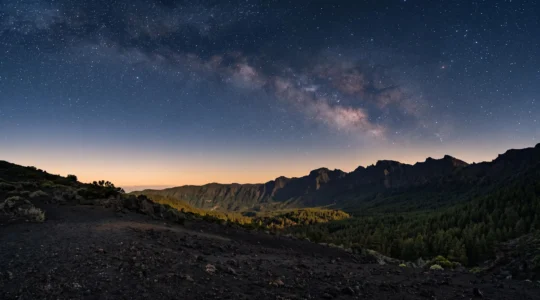 Paysage panoramique de La Palma illustrant le contraste entre terre volcanique noire, forêt luxuriante et ciel étoilé