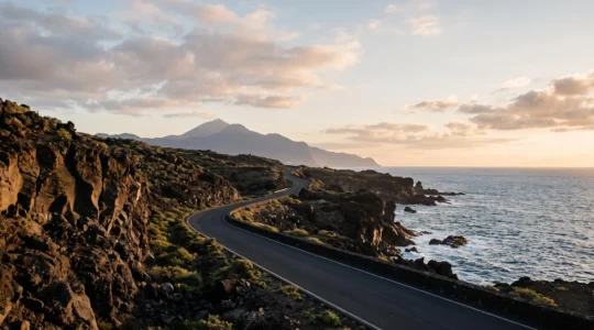 Route côtière sinueuse traversant un paysage volcanique spectaculaire entre montagnes et océan Atlantique, évoquant le choix d'un itinéraire de voyage aux Canaries
