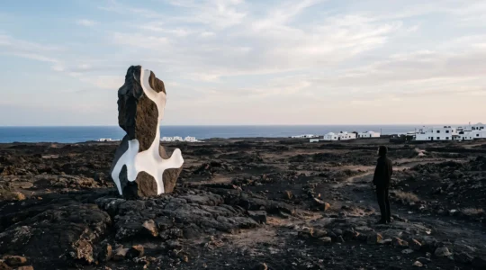 Sculpture d'art contemporain integree dans un paysage volcanique des Canaries au lever du soleil
